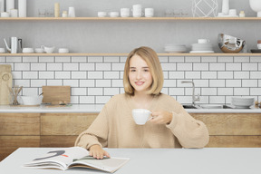 A woman sitting at a table with a cup of coffee and a magazine