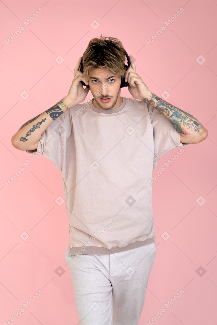 Attractive young guy pulling off his headphones