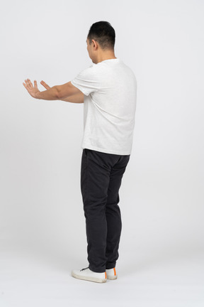Вид в три четверти на человека в повседневной одежде, стоящего с вытянутыми руками
