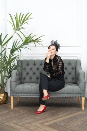 Woman sitting on couch next to a potted plant and giggling