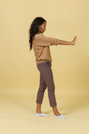 Vista lateral de uma jovem mulher de pele escura estendendo as mãos