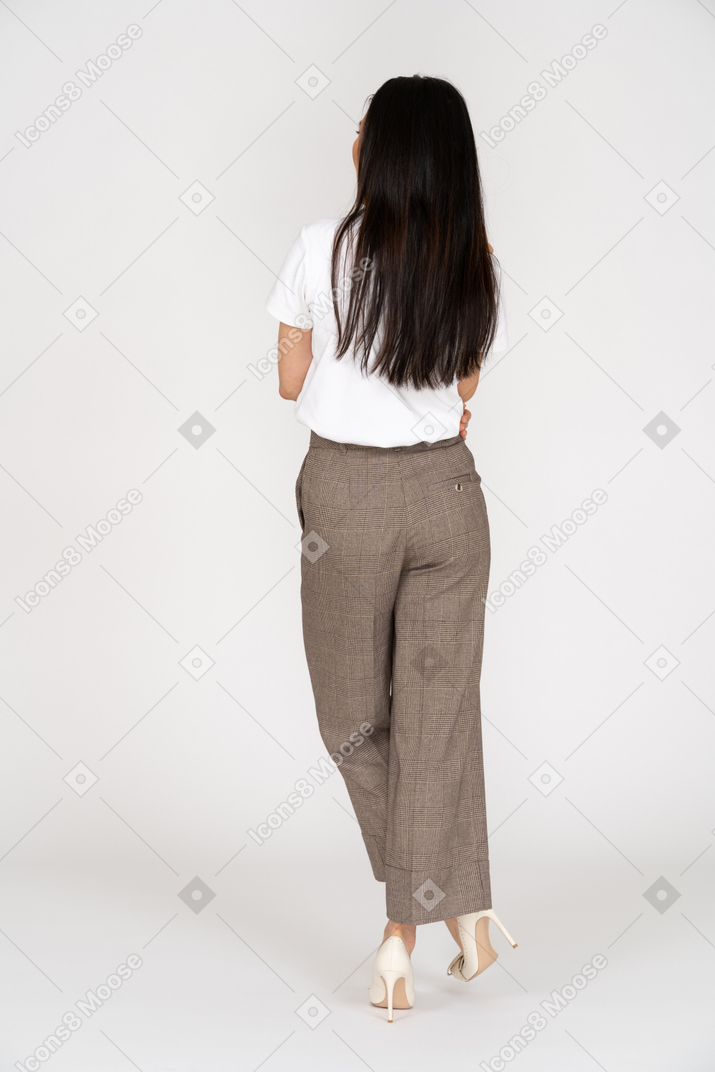 Vista traseira de uma jovem de calça cruzando as pernas