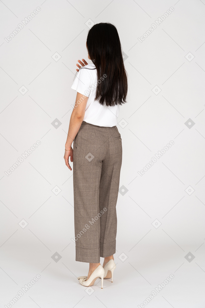 Three-quarter back view of a young woman in breeches touching her shoulder