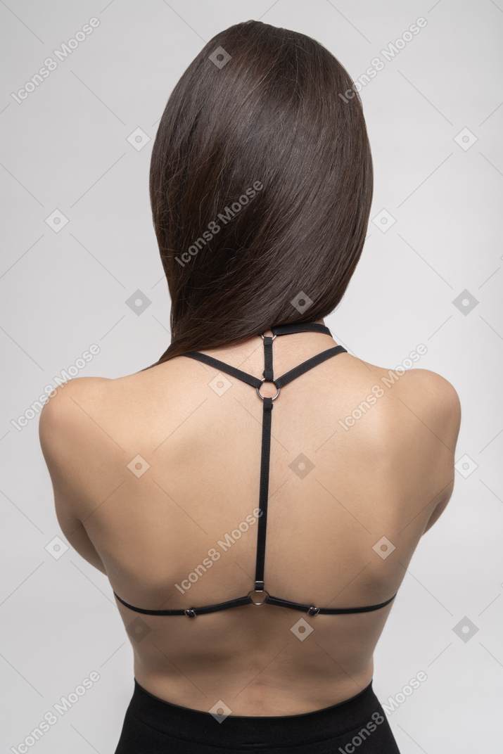 ハーネスのセクシーな若い女性の背面図
