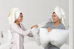 Women in pyjamas fighting with pillows