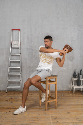 Vista de tres cuartos de un hombre en un taburete balanceando un ukelele