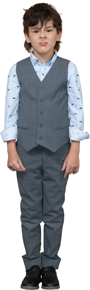 Front view of a cute boy in grey suit making faces and looking at camera