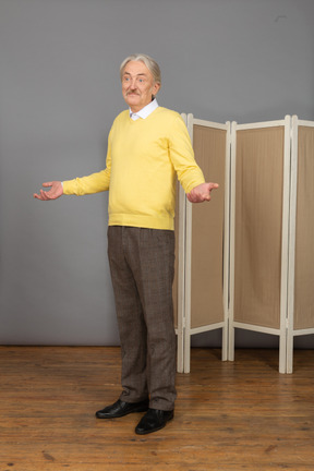 Vista de tres cuartos de un anciano perplejo levantando las manos mientras mira a un lado