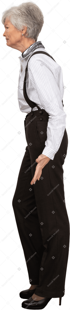 Вид сбоку гримасничающей старушки в офисной одежде, раскинувшей руки
