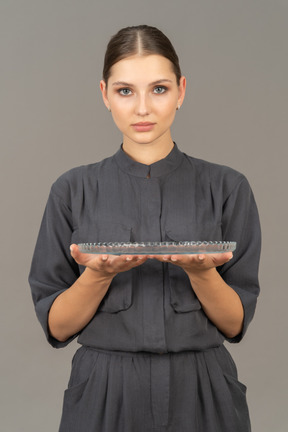 Front view of a young woman in a jumpsuit holding glass plate