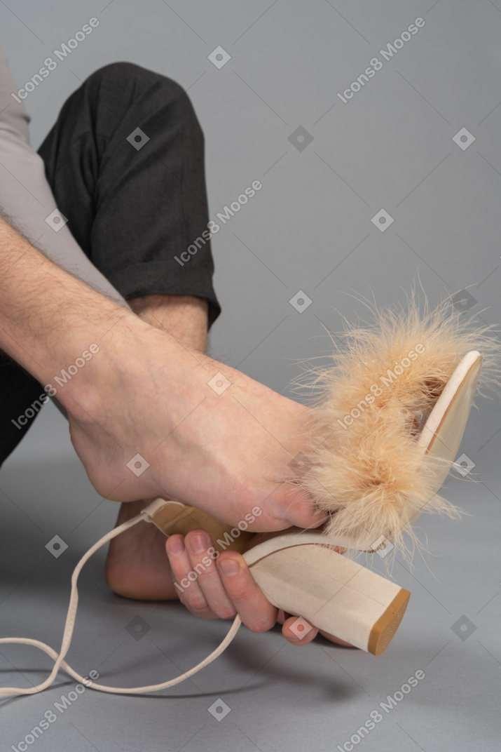 Unrecognizable man trying on female high heel shoes