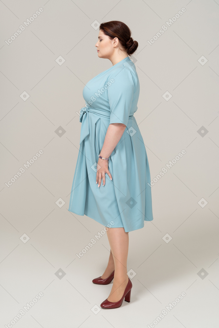 Donna in abito blu in piedi di profilo