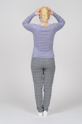 Vista traseira de uma mulher em roupas casuais, descansando as mãos no topo da cabeça