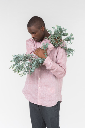 Good looking young man holding green branches