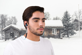 A man is standing in front of a cabin in the snow