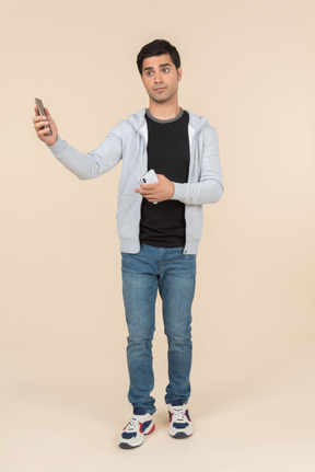 Junger kaukasischer mann, der ein smartphone anhält und auf einem anderen schaut