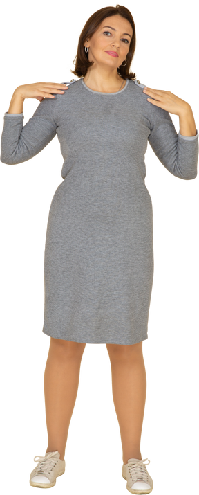 Front view of a woman in grey dress standing with hands on shoulders