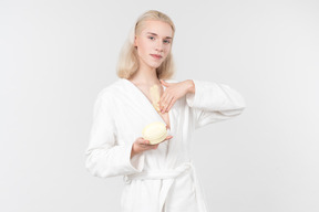 Young blond-haired man in a white bathrobe going about his morning routine