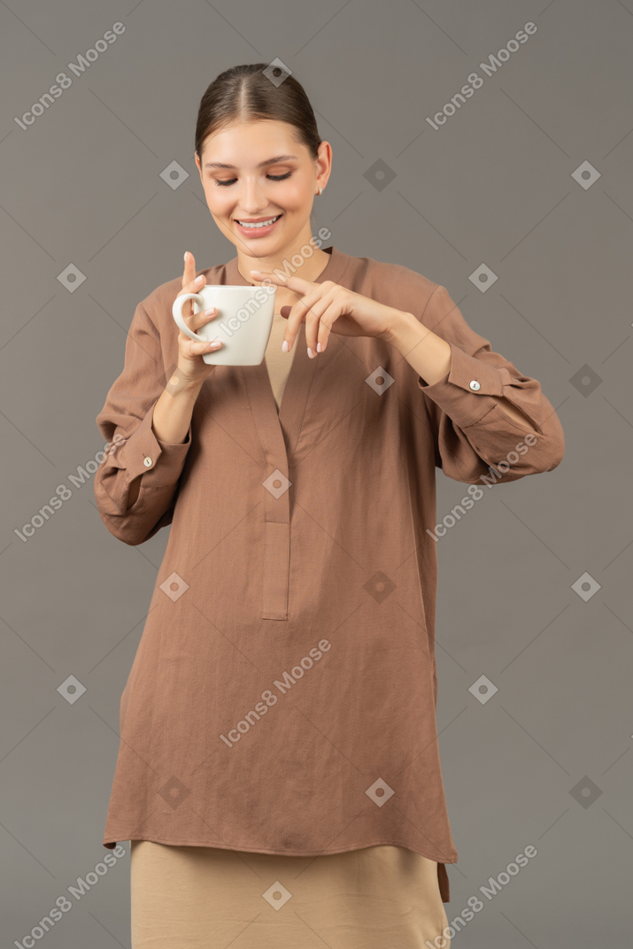 笑顔の若い女性はコーヒーカップを持っています