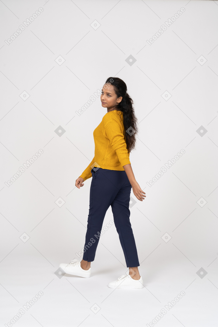 Vista lateral de uma garota com roupas casuais caminhando