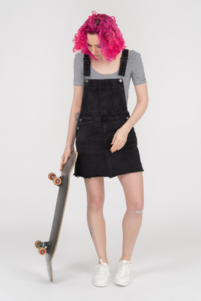 Giovane donna dai capelli rosa con uno skateboard