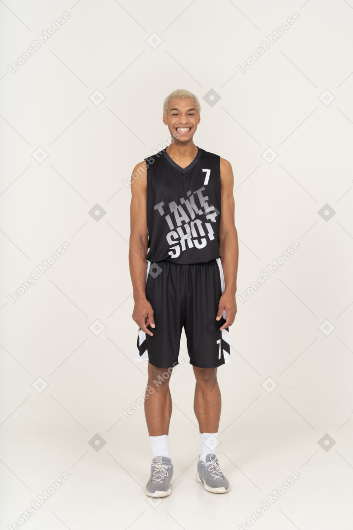 Vista frontale di un giovane giocatore di basket maschio sorridente in piedi immobile