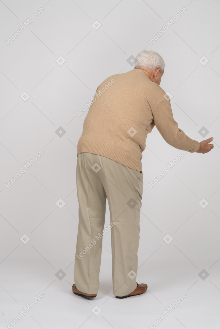 一位身着休闲服的老人做欢迎手势的后视图