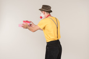 Male clown holding gift box and standing back to camera