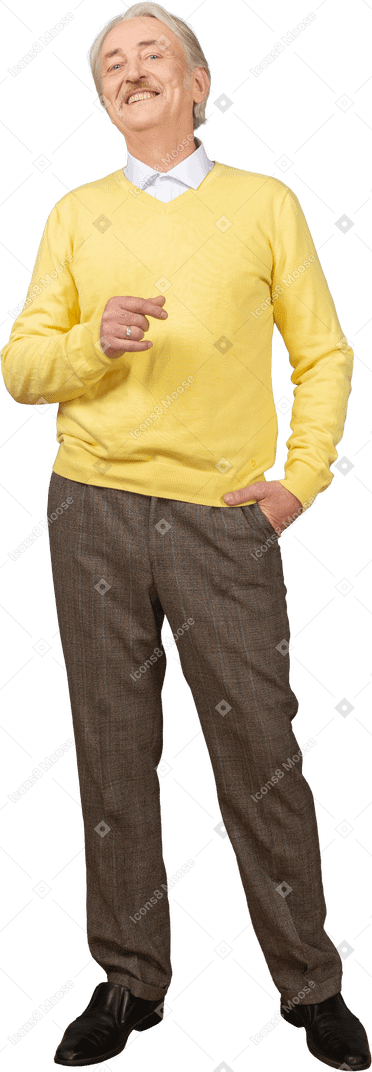 Vue de face d'un vieil homme souriant heureux dans un pull jaune levant la main et regardant la caméra