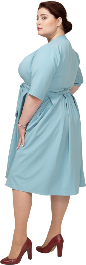 Mulher de vestido azul em pé de perfil