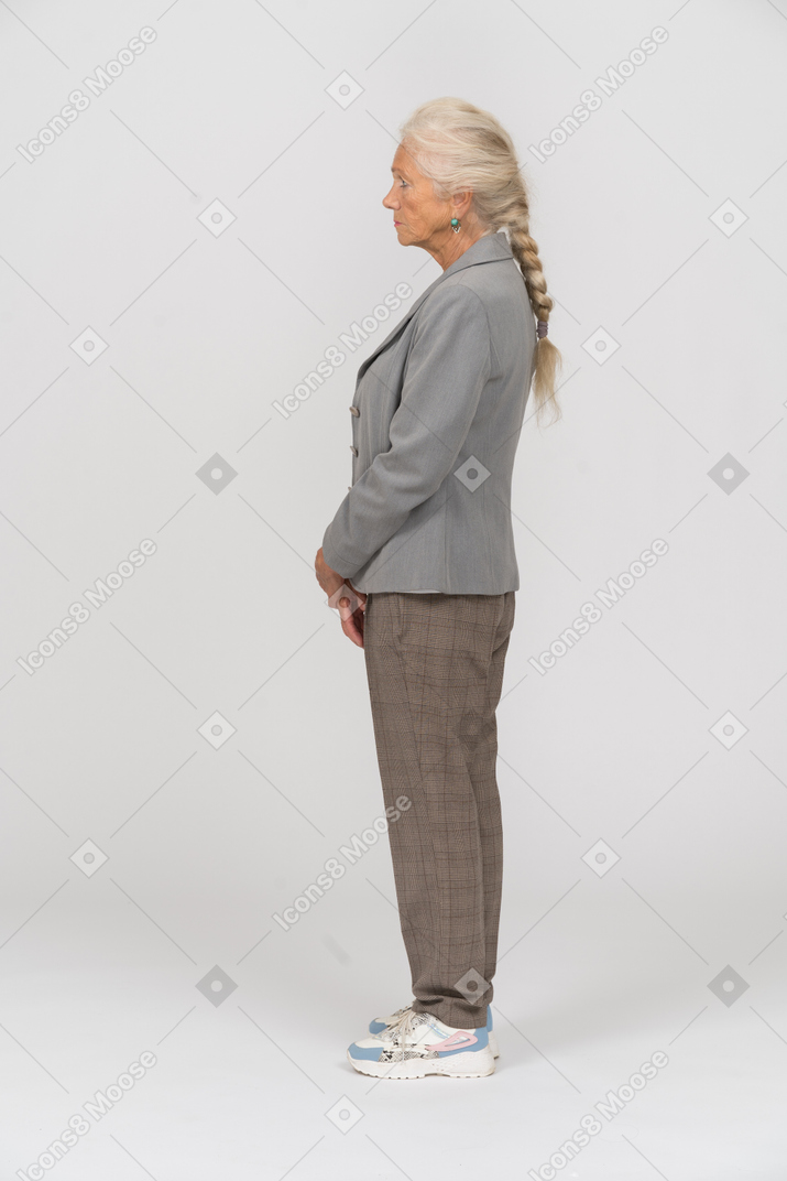 Vecchia donna in abito in piedi di profilo
