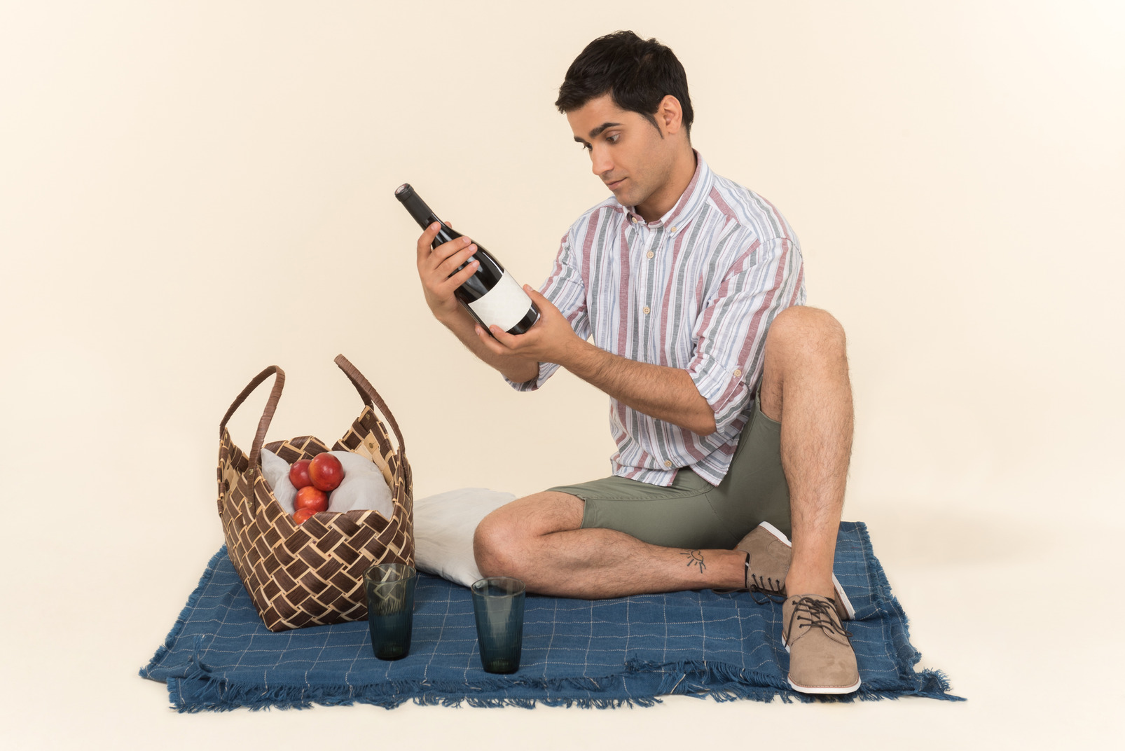 Young caucasian guy sitting on blanket and looking at bottle