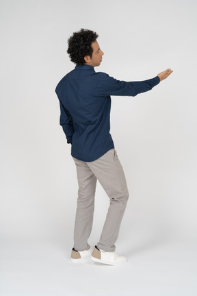 Rear view of a man in casual clothes pointing with a hand