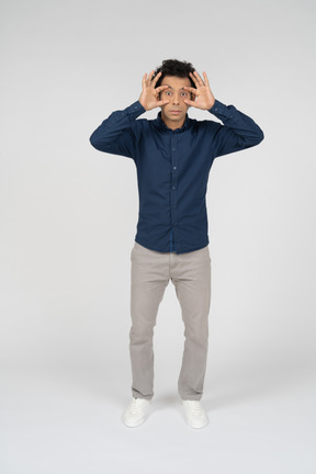 Vista frontal de um homem com roupas casuais olhando através de binóculos imaginários