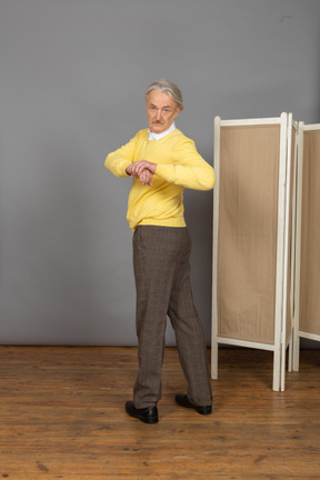 Back view of an old man exercising by making rotation