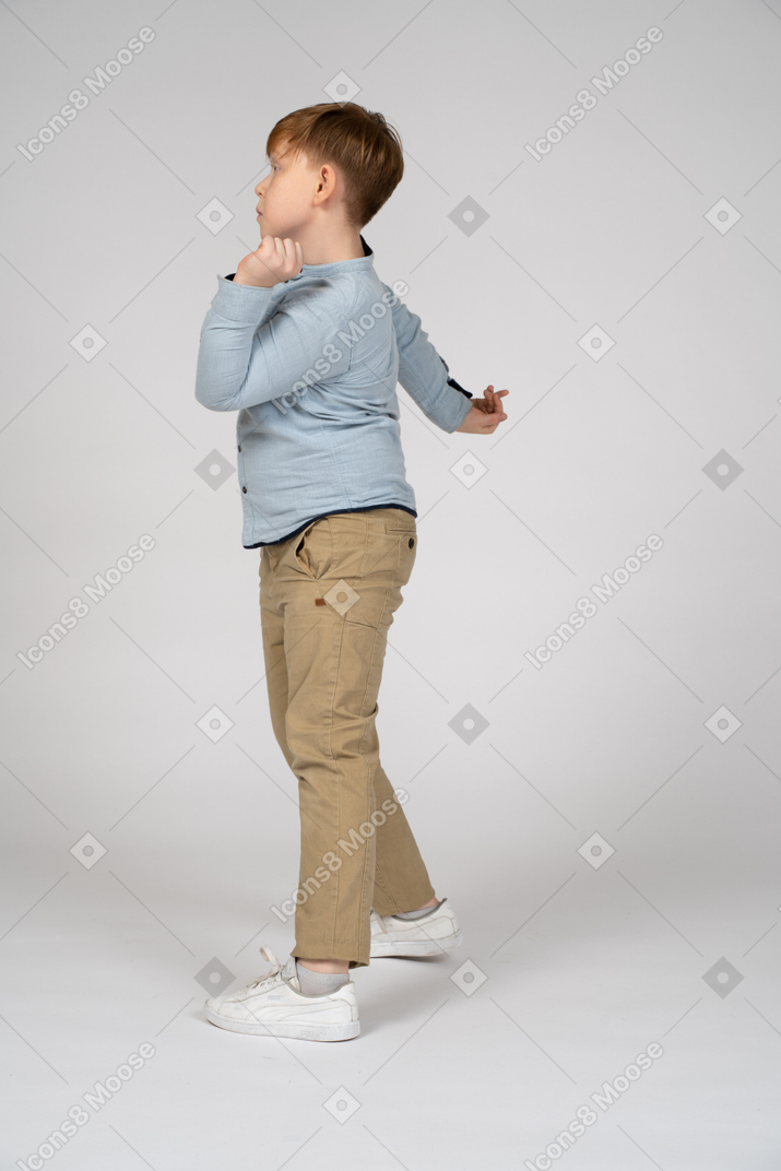 Side view of a young boy doing a graceful pose