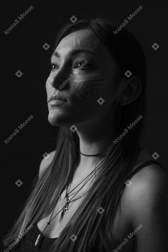 Foto noir de vista lateral de uma jovem com arte no rosto olhando de lado