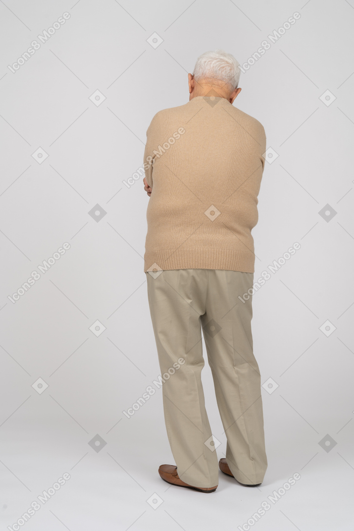一位身穿休闲服、双臂交叉站立的老人的后视图