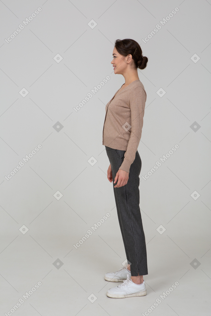 一个微笑的女性，穿着套头衫和裤子的侧视图
