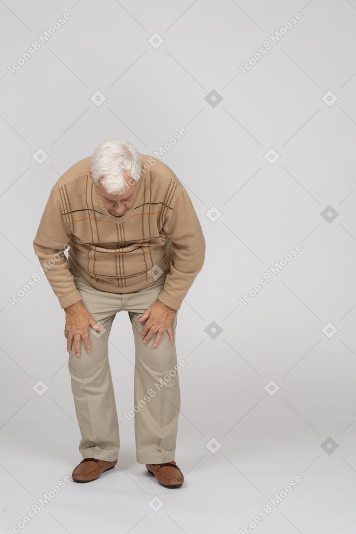 Front view of an old man in casual clothes bending down