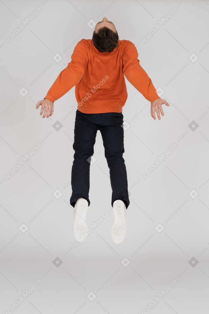 Молодой человек в оранжевой толстовке прыгает