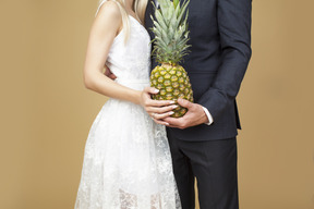 Bride and groom hugging and holding a pineapple