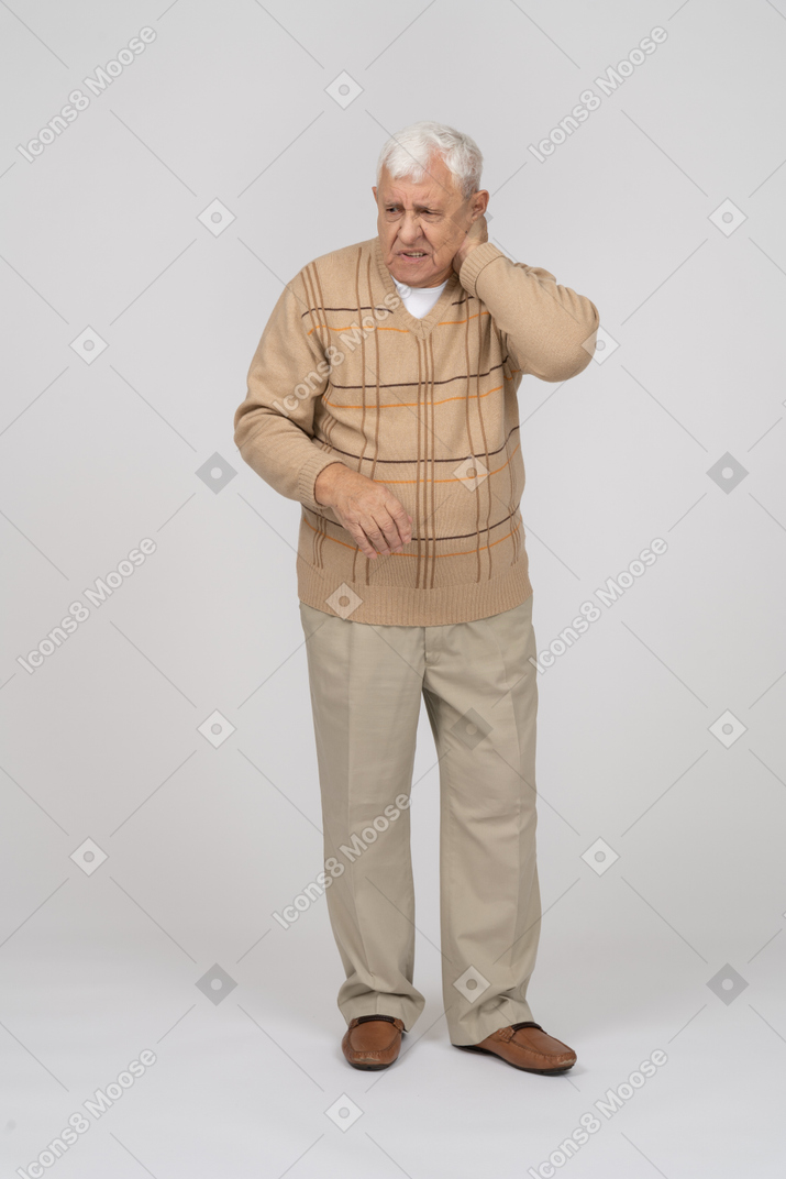 Front view of an old man in casual clothes suffering from pain in neck