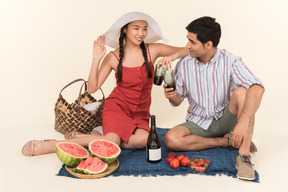 年轻的异族夫妇野餐和喝葡萄酒
