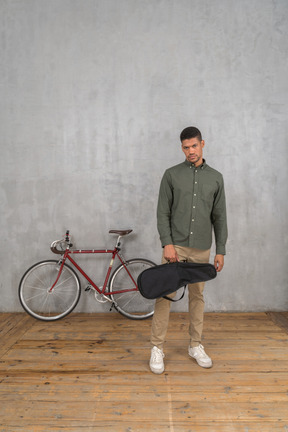 Vista frontal de un hombre vestido de forma informal con un estuche de ukelele