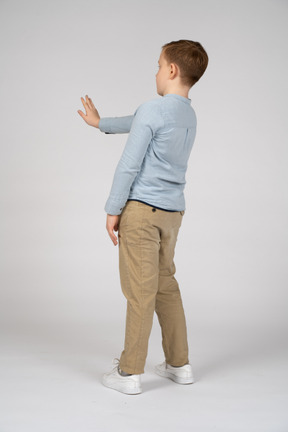 Vista laterale di un ragazzo di un ragazzo in piedi con il braccio esteso
