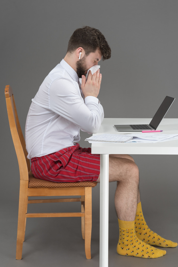 Sick young man trying to work remotely