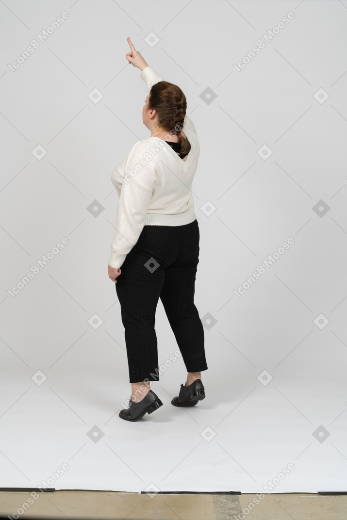 一位身着休闲服、举起手臂站立的胖女人的后视图