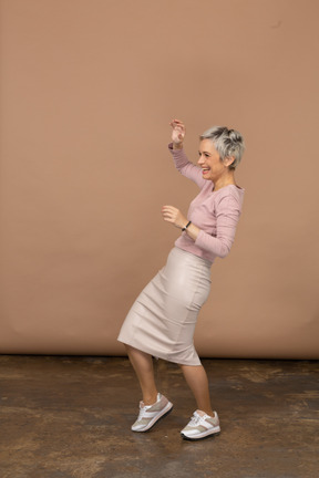 Vista lateral de una mujer feliz en ropa casual bailando