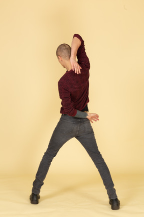 Back view of a young man in red pullover stretching his arm